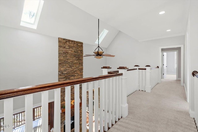 hallway with recessed lighting, light carpet, an upstairs landing, vaulted ceiling with skylight, and plenty of natural light