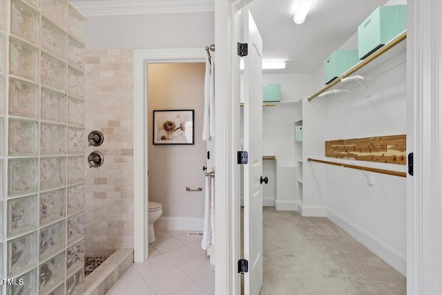 bathroom with tile patterned flooring, walk in shower, toilet, and baseboards