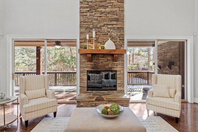 living area with dark wood-style floors, a fireplace, a high ceiling, and a ceiling fan