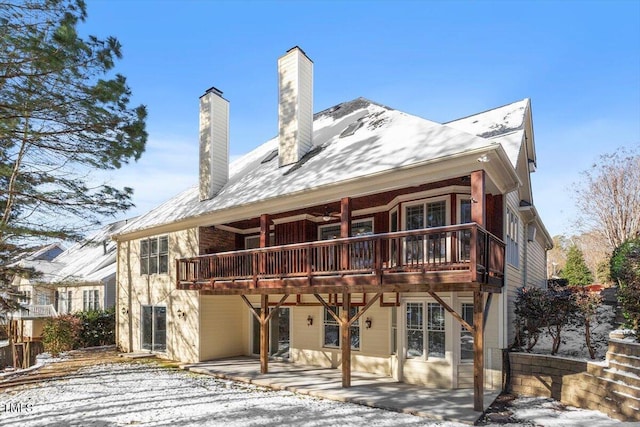 snow covered house with a chimney and a patio area