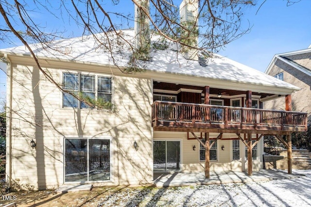 snow covered back of property featuring a patio area