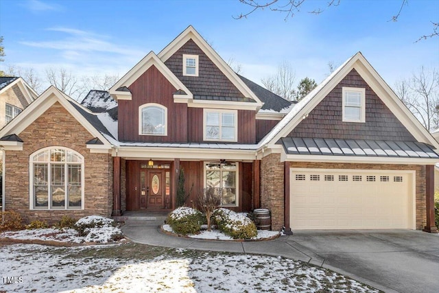 craftsman inspired home with driveway, a garage, stone siding, metal roof, and a standing seam roof