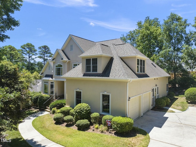 view of side of home featuring concrete driveway, roof with shingles, a lawn, and stucco siding