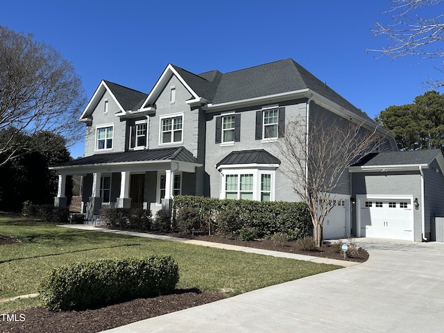 view of front facade with driveway, covered porch, a front lawn, and a standing seam roof