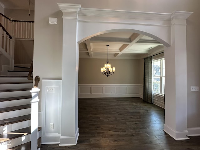 unfurnished dining area featuring arched walkways, coffered ceiling, dark wood-type flooring, stairs, and beam ceiling