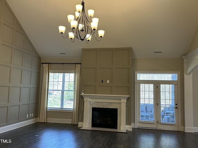 unfurnished living room featuring dark wood-style flooring, lofted ceiling, visible vents, a high end fireplace, and baseboards