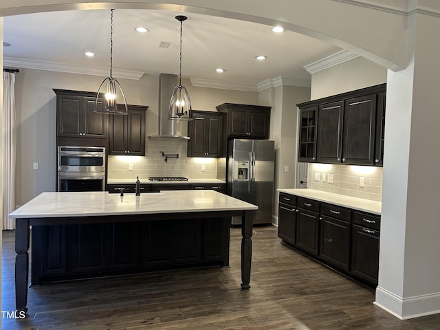 kitchen featuring wall chimney exhaust hood, a kitchen island with sink, a breakfast bar area, and stainless steel appliances