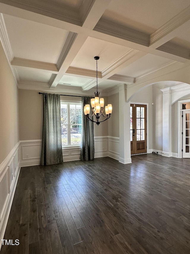 empty room featuring plenty of natural light, beam ceiling, arched walkways, and dark wood-style flooring