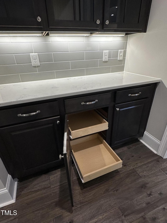 room details with dark wood-type flooring, decorative backsplash, and dark cabinets