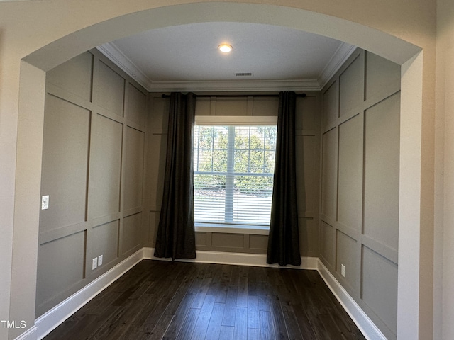 spare room with crown molding, arched walkways, and a decorative wall