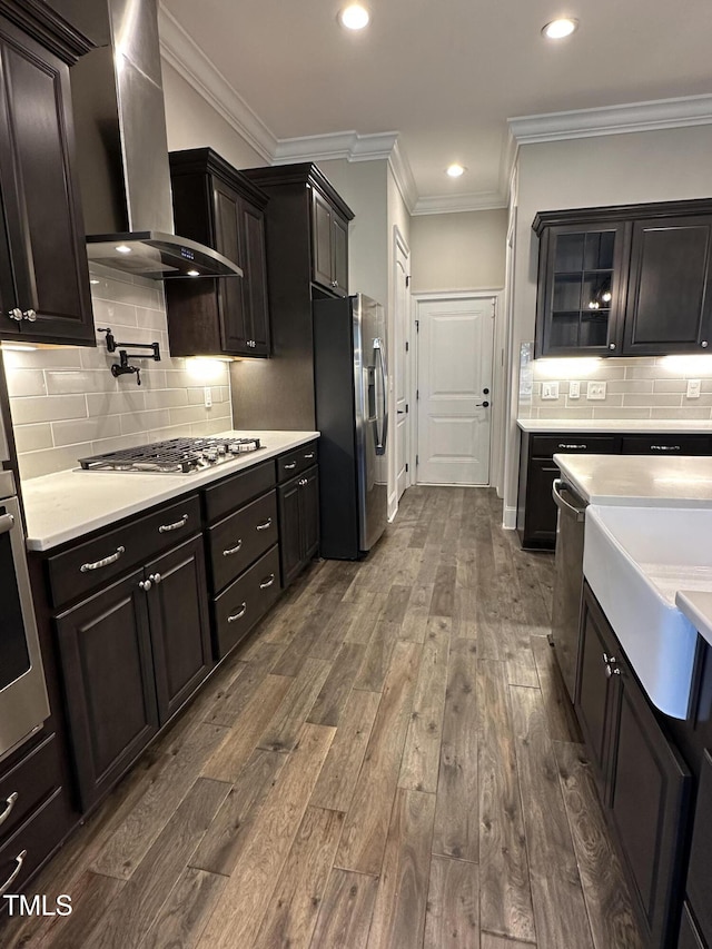 kitchen featuring dark wood finished floors, stainless steel appliances, light countertops, glass insert cabinets, and wall chimney exhaust hood