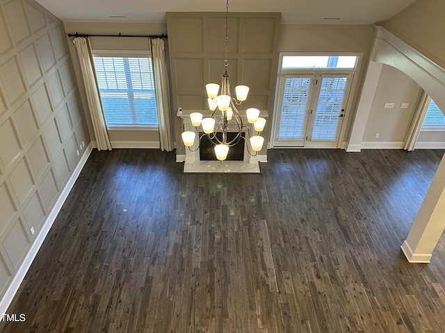 interior space with arched walkways, dark wood-style flooring, a chandelier, and baseboards