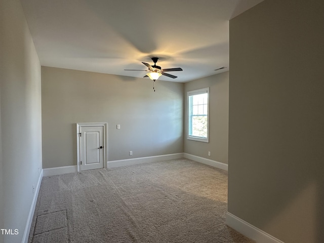 spare room with light carpet, visible vents, baseboards, and ceiling fan