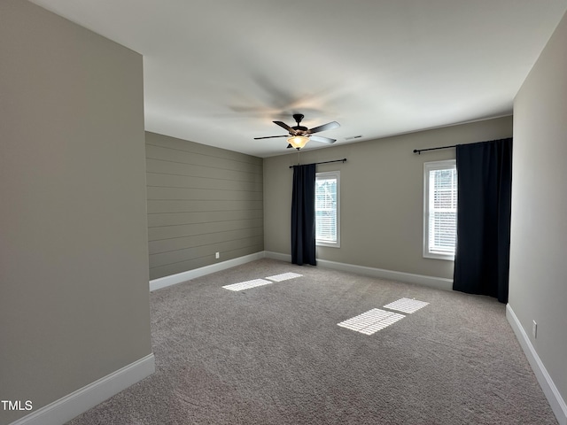 empty room featuring baseboards, a ceiling fan, visible vents, and light colored carpet