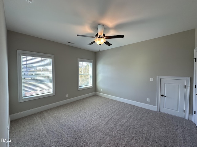 carpeted spare room featuring ceiling fan, visible vents, and baseboards