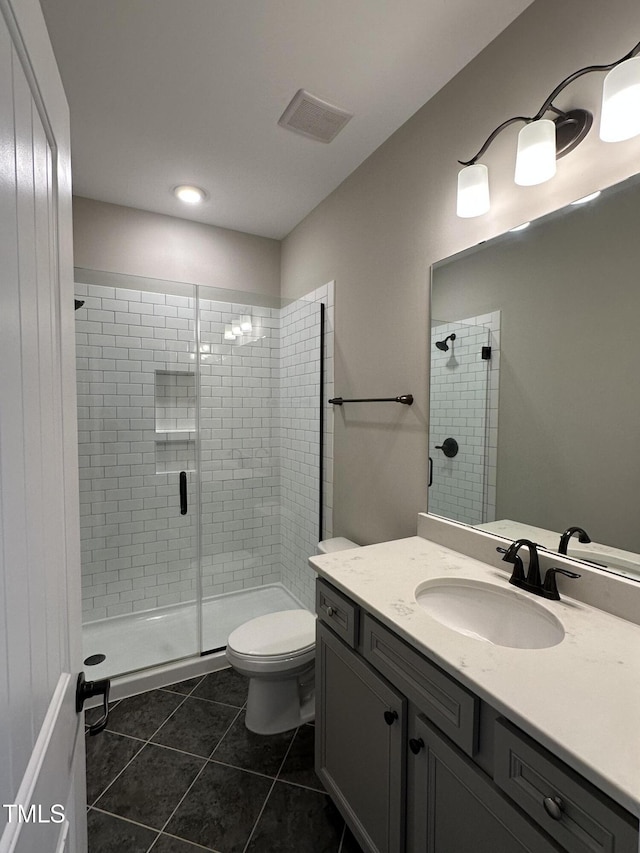 full bath featuring toilet, visible vents, vanity, a shower stall, and tile patterned floors