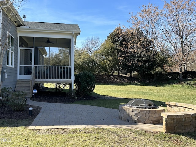 view of yard featuring an outdoor fire pit, a patio, a sunroom, ceiling fan, and stairway