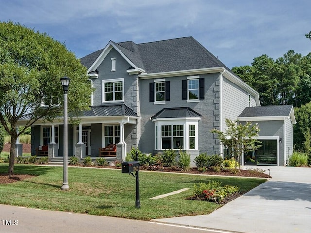 view of front of home featuring a porch, a front yard, a standing seam roof, and driveway