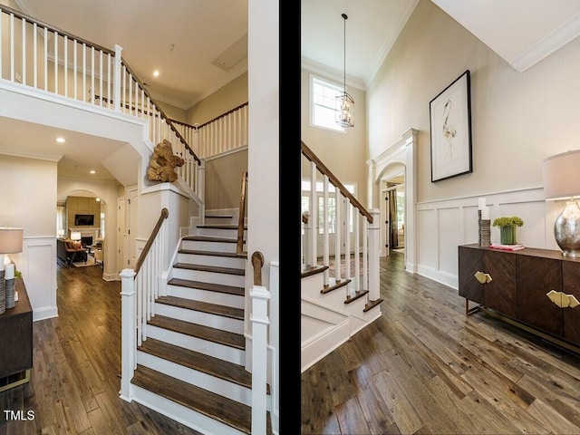 staircase with crown molding, arched walkways, a decorative wall, and wood finished floors