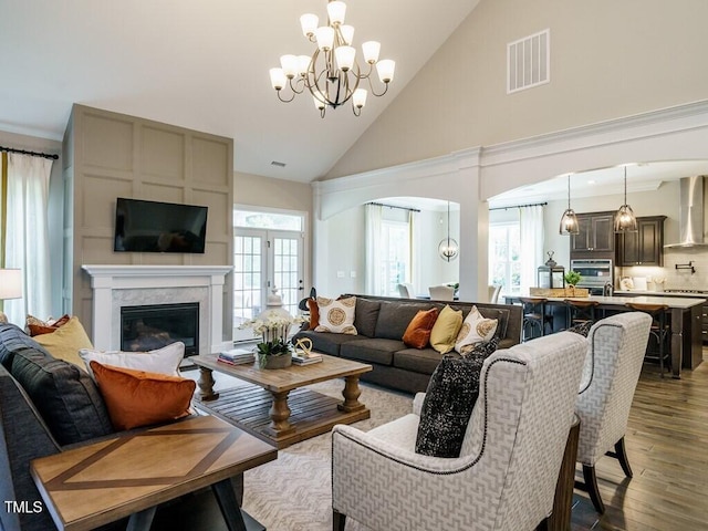 living room featuring plenty of natural light, wood finished floors, visible vents, and a high end fireplace