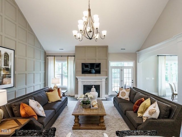 living area featuring visible vents, a premium fireplace, an inviting chandelier, high vaulted ceiling, and a decorative wall