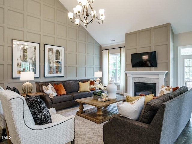 living room with high vaulted ceiling, a decorative wall, and a glass covered fireplace