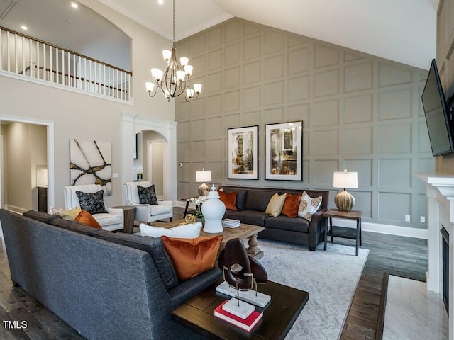 living room featuring arched walkways, dark wood finished floors, a premium fireplace, a chandelier, and a decorative wall