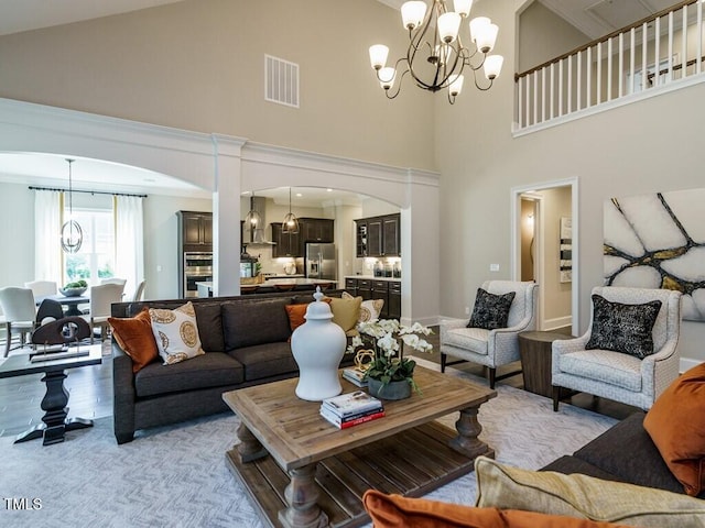 living area with a chandelier, arched walkways, light wood-type flooring, and visible vents