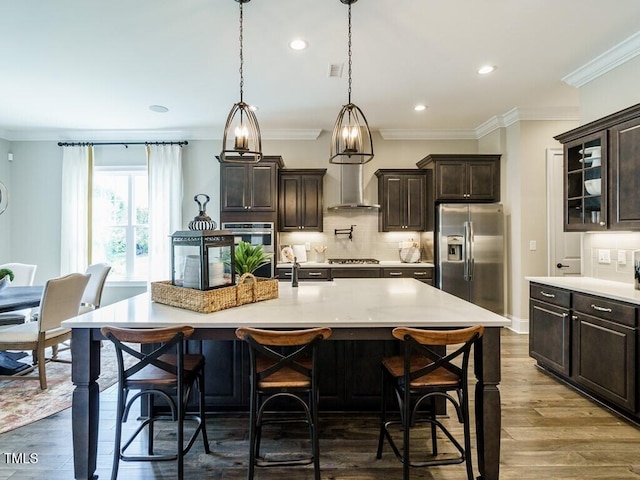 kitchen featuring appliances with stainless steel finishes, light countertops, a center island with sink, and a breakfast bar area