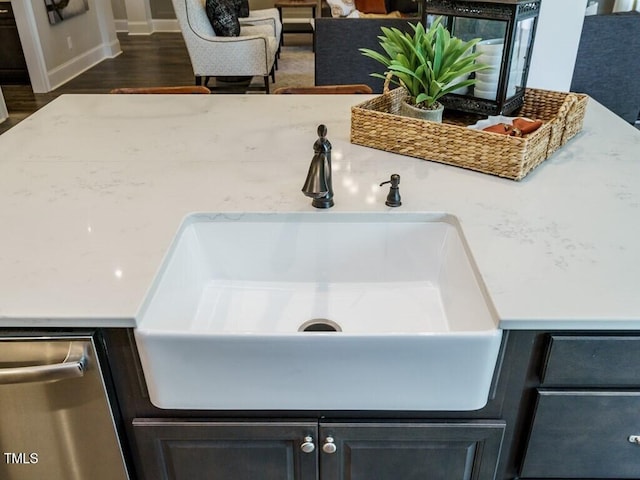 details featuring stainless steel dishwasher, dark wood-style flooring, light countertops, and a sink