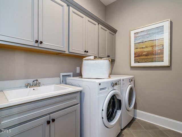 laundry area featuring cabinet space, washing machine and dryer, a sink, dark tile patterned floors, and baseboards