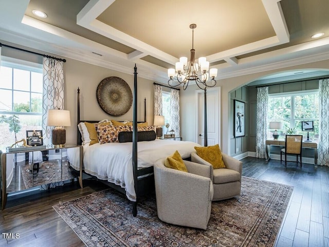 bedroom featuring dark wood-type flooring, a tray ceiling, multiple windows, and arched walkways