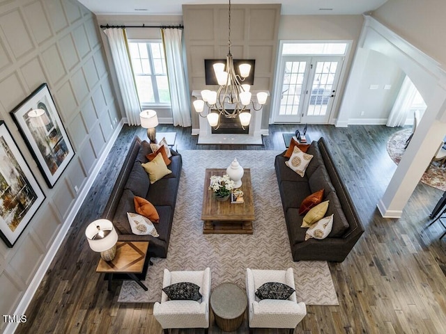 living area with baseboards, a chandelier, and wood finished floors