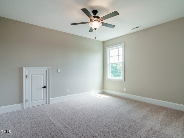 carpeted empty room with a ceiling fan, visible vents, and baseboards