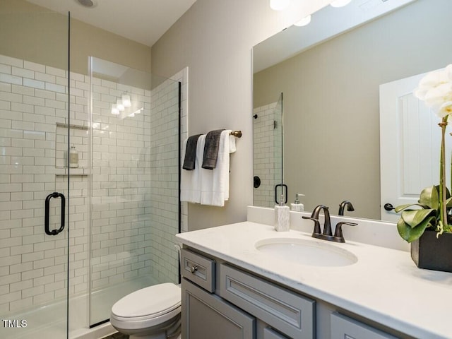 full bath with a shower stall, vanity, and toilet