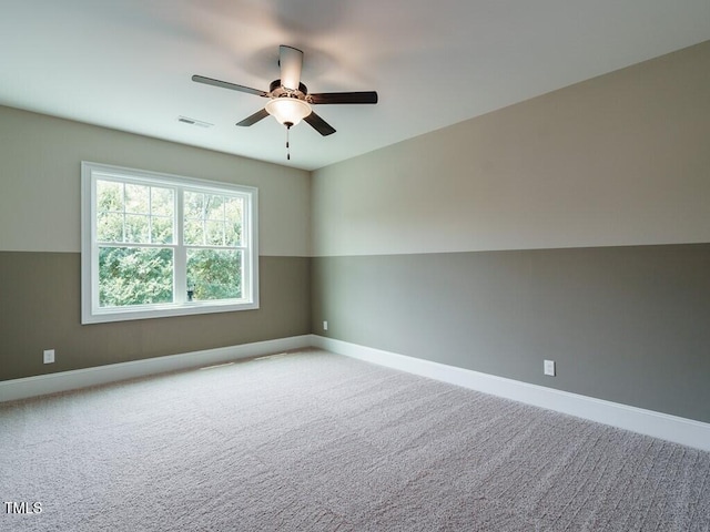 carpeted spare room with baseboards, visible vents, and ceiling fan