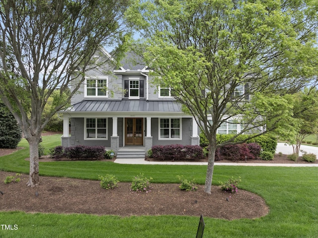 view of front of home featuring metal roof, a standing seam roof, covered porch, and a front yard