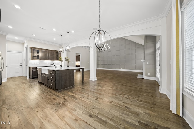 kitchen with light countertops, arched walkways, crown molding, dark brown cabinetry, and open floor plan