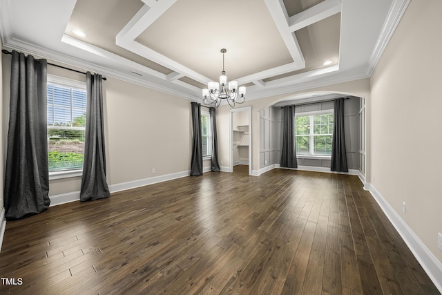 empty room with arched walkways, dark wood finished floors, an inviting chandelier, and crown molding