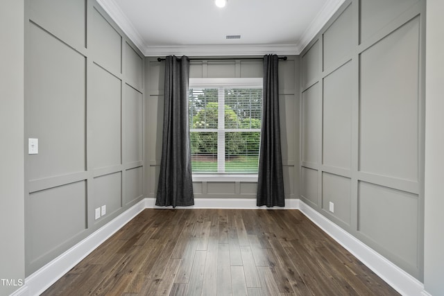 unfurnished room featuring dark wood-style floors, ornamental molding, and a decorative wall