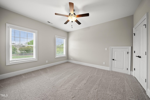 unfurnished room featuring baseboards, a ceiling fan, visible vents, and light carpet