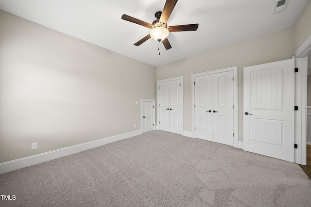 unfurnished bedroom with carpet floors, visible vents, baseboards, and multiple closets