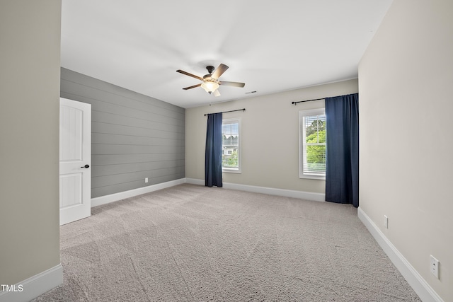 carpeted spare room featuring baseboards and a ceiling fan