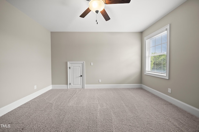 carpeted spare room with ceiling fan and baseboards