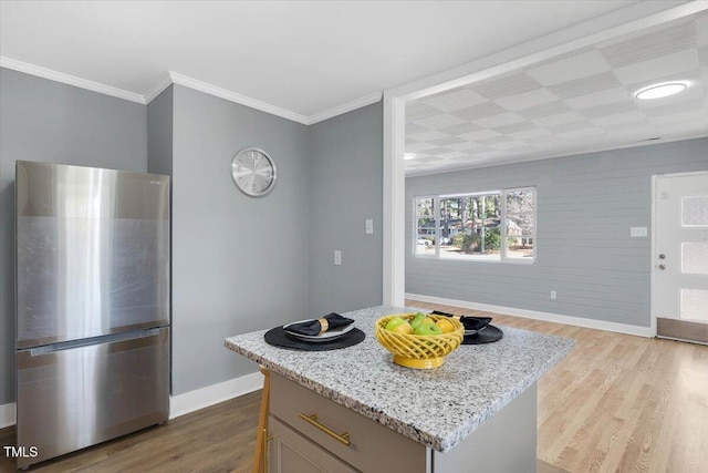 kitchen featuring light wood-type flooring, light stone countertops, stainless steel refrigerator, and a kitchen island