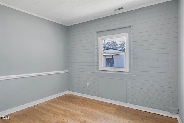 spare room featuring ornamental molding and light wood-type flooring