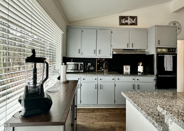 kitchen featuring double oven, backsplash, ornamental molding, vaulted ceiling, and dark stone counters