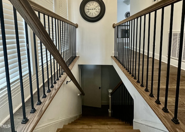 staircase with hardwood / wood-style floors and a high ceiling