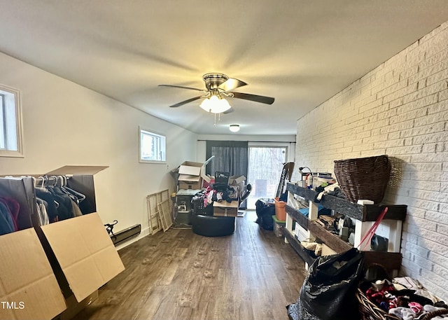 interior space featuring dark wood-type flooring, ceiling fan, and brick wall