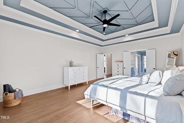 bedroom featuring a raised ceiling, crown molding, baseboards, and wood finished floors